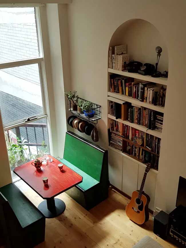 A bright red tabletop and a long green bench make a corner feel like a dedicated dining spot with personality.