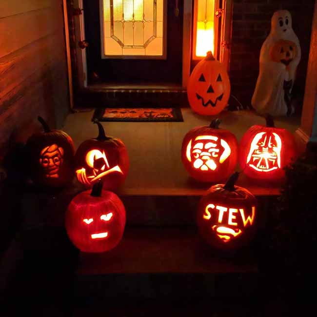 It looks like the whole family got involved in this pumpkin carving session. Their porch is filled with several lit pumpkins, each showing a different fun design or character.