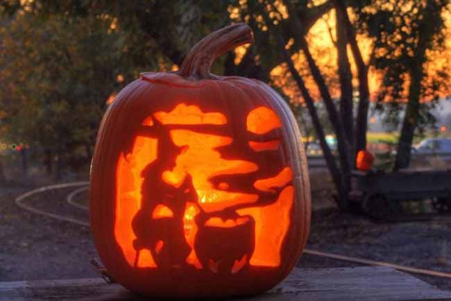 Against a beautiful sunset, this pumpkin tells a story with its carving of a witch and her cat stirring a cauldron.