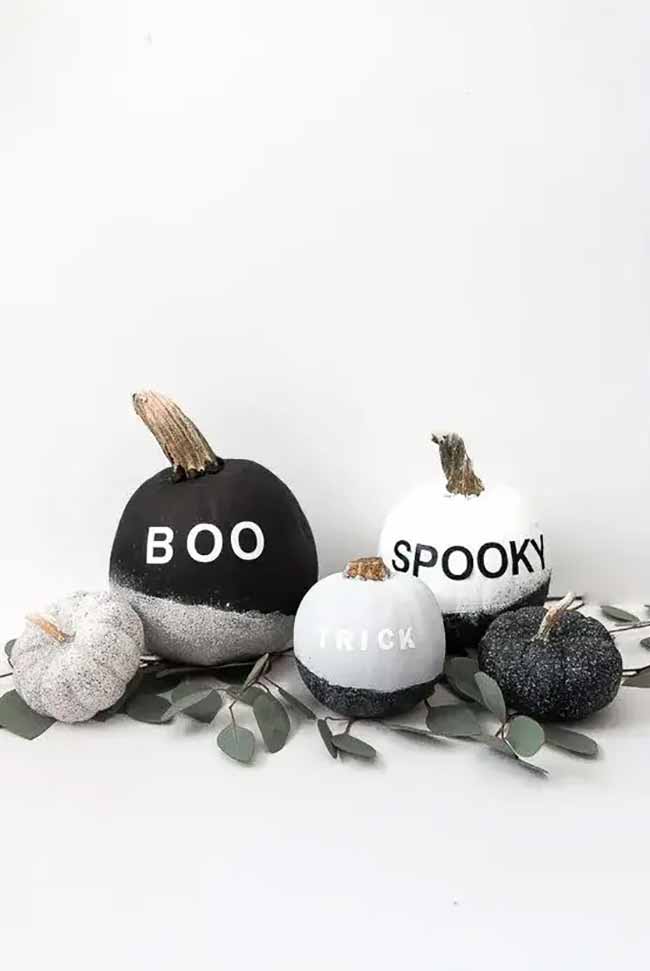 A modern and chic collection of pumpkins is painted in a black and white theme, dipped in silver glitter, and labeled with simple words like "Boo," "Spooky," and "Trick."