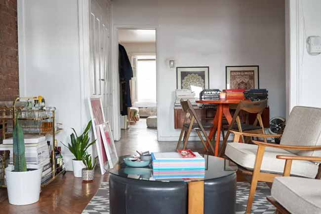 A plush leather ottoman sits front and center, surrounded by mid-century furniture and a stylish bar cart.