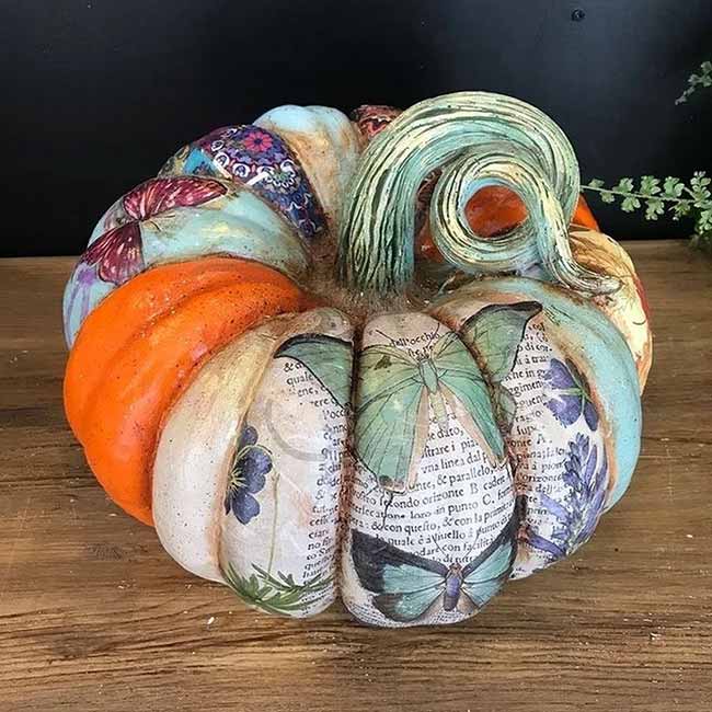 A pumpkin decorated with decoupaged papers, from floral prints to butterflies and vintage book pages.
