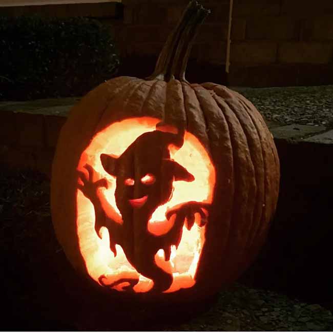 Look at this ghost! It's carved into a pumpkin at night, and it looks like it's dancing under a full moon.