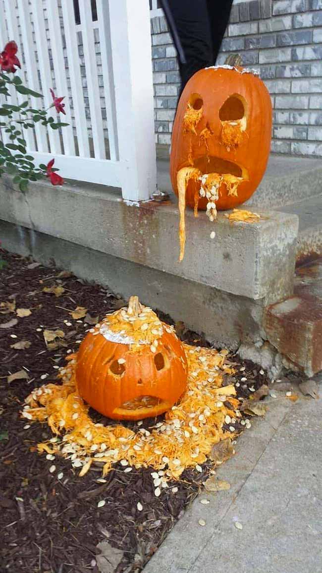 Someone made a pumpkin carving that looks like it's throwing up pumpkin guts and seeds all over the ground. It's a funny, messy Halloween decoration.