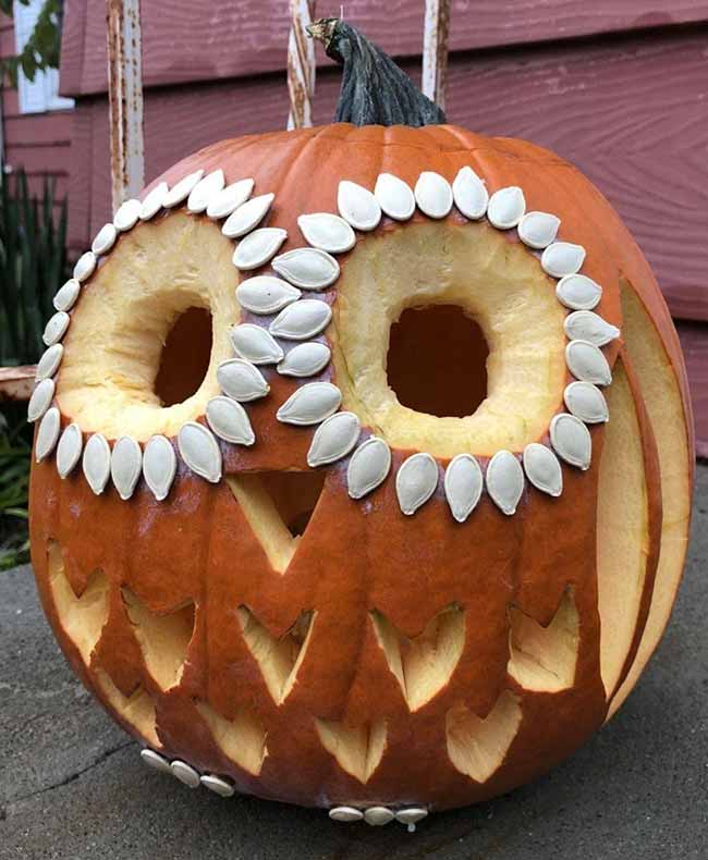 This cute pumpkin carving looks like an owl, and it's decorated with pumpkin seeds around the eyes to create a feathery effect.