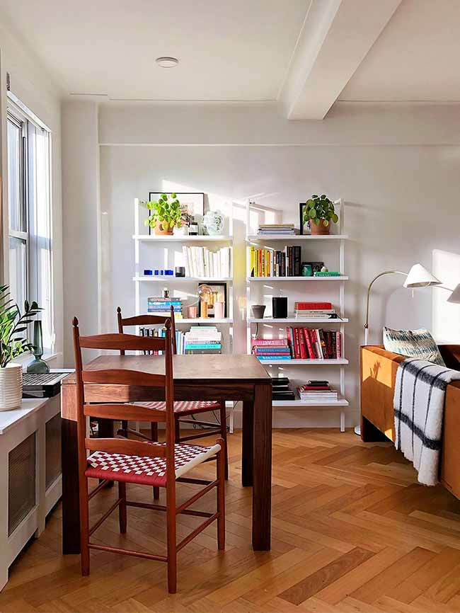 You don’t need to build walls to separate areas. Put your dining table in front of a bookcase or tall shelves, and it instantly feels like its own zone. The shelves act as a backdrop, add storage, and give the space more personality at the same time.