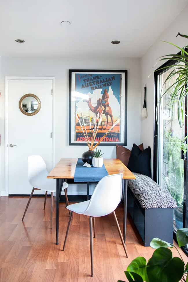 You can create a small living room with dining table by tucking a bench against the window with a geometric cushion and wall art above.