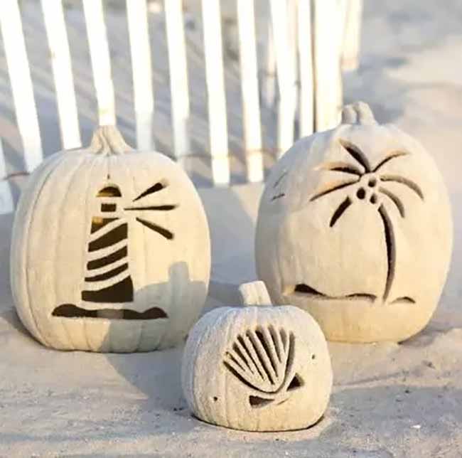 These pumpkins are decorated with a beach theme, with a lighthouse, a seashell, and a palm tree carved into their sides. It's a unique take on pumpkin carving.