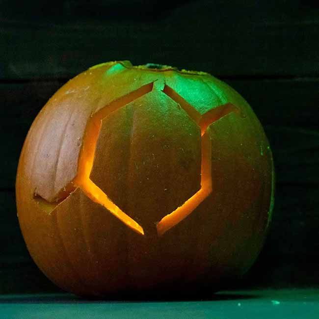 This pumpkin has a simple hexagonal shape carved into it. A green light gives it a cool, modern look.