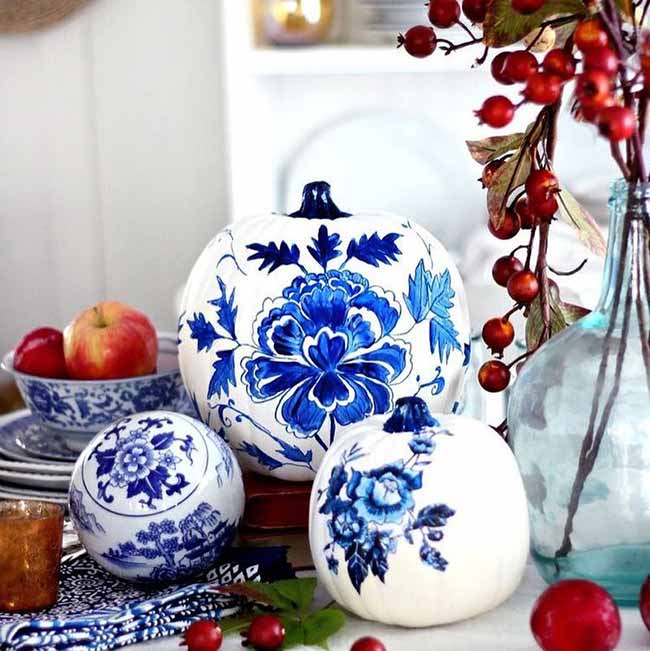 A collection of pumpkins is decorated in classic blue-and-white porcelain style, including one large pumpkin with a bold central floral motif.