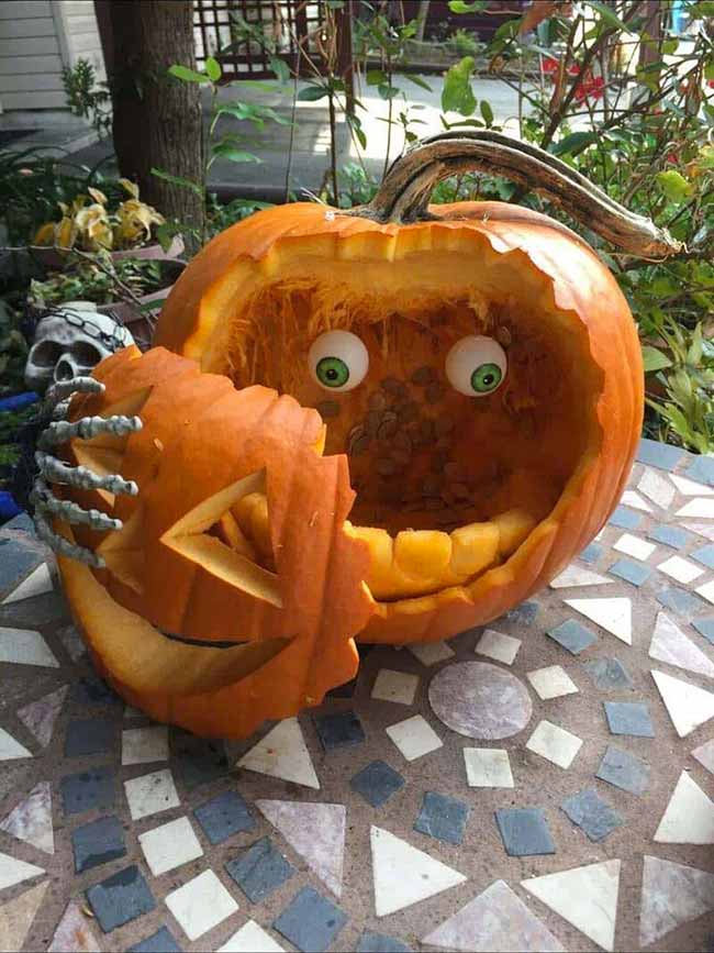 A skeleton hand holds this pumpkin's face, revealing some huge, fake eyes inside.