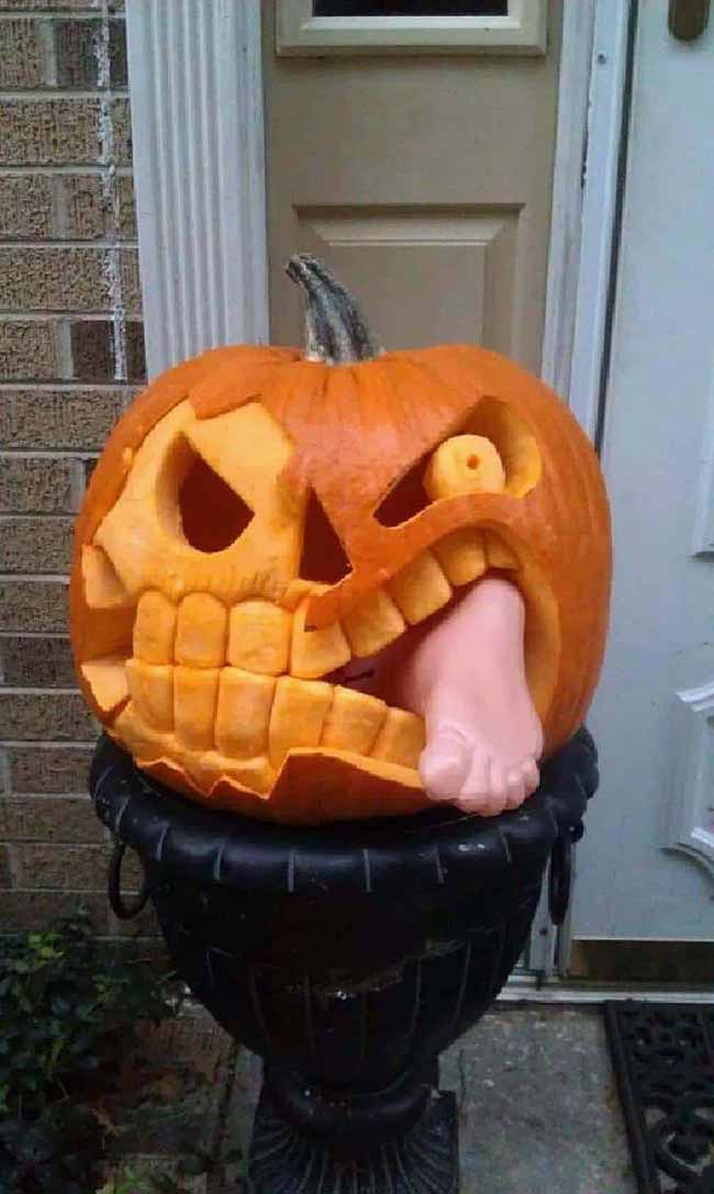 Looking at this pumpkin, you can't help but smile. It has a mouthful of big teeth and is playfully "eating" a fake human foot.