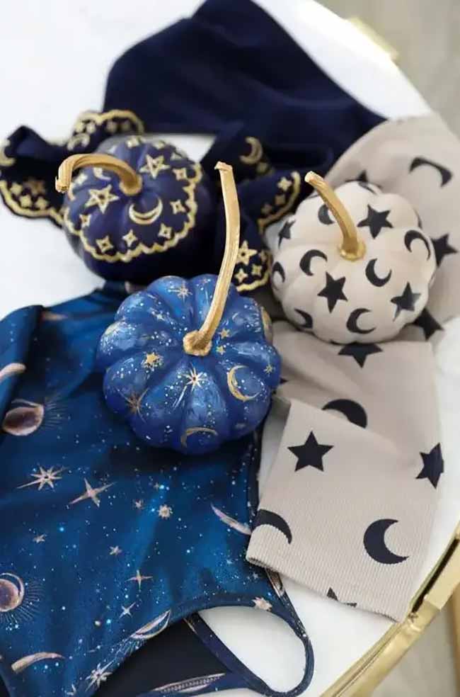 Against a dark background, pumpkins painted in a starry galaxy pattern feature shimmering gold constellations for a mystical effect.