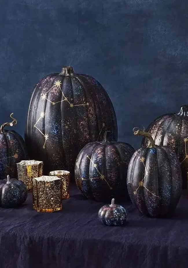 These celestial-themed pumpkins—two dark and one light—are painted with golden stars and moons for a dreamy Halloween display.