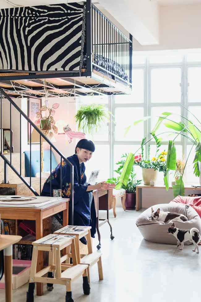 Loft stairs, leafy plants, and two tiny dogs on a beanbag make this open space feel playful and lived-in.