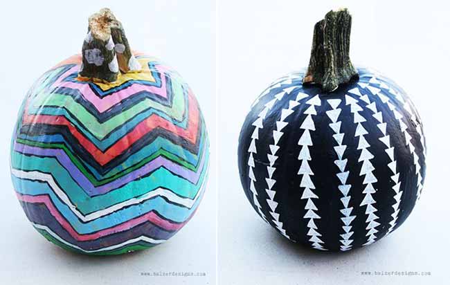 Two pumpkins sit side by side—one with a multicolored zigzag pattern, the other dark with white triangles—showcasing contrasting artistic styles.