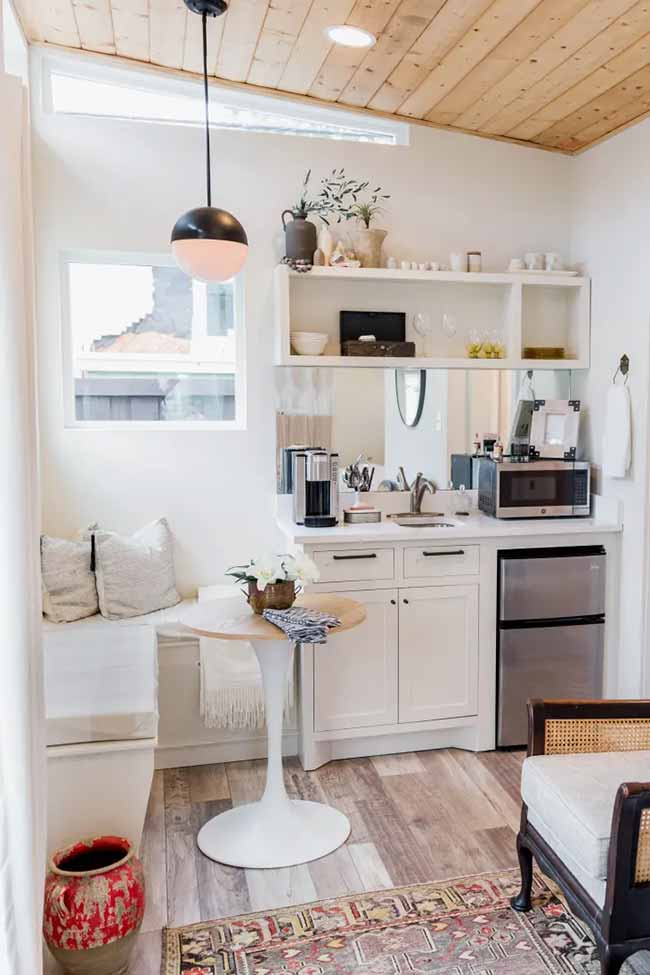 A round white table with an L-shaped cushioned bench makes this cozy studio surprisingly comfortable for dining.