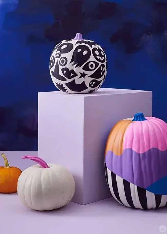 A pumpkin is painted in black-and-white comic style, covered with Halloween-themed doodles including ghosts, skulls, and eyeballs.